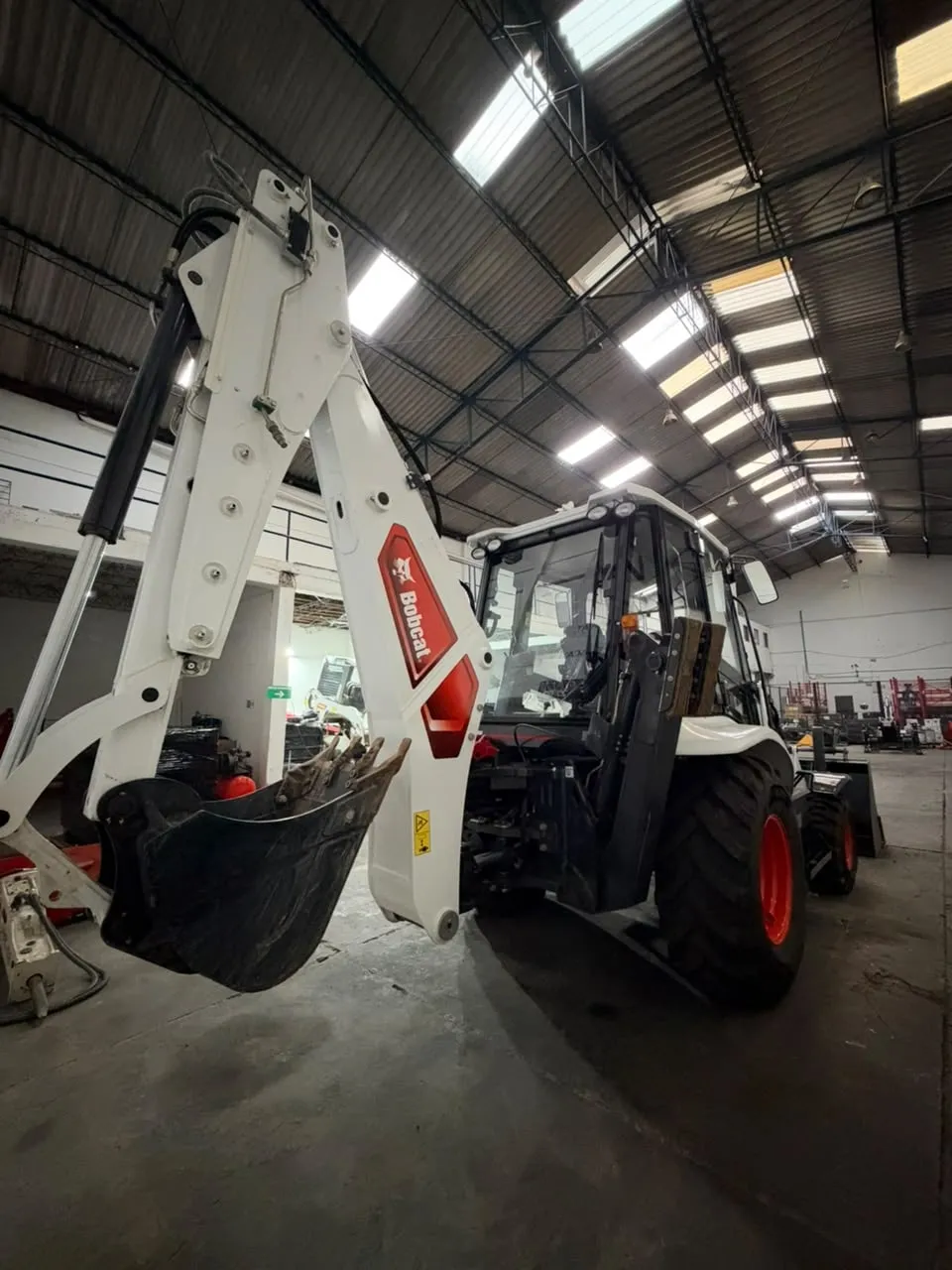 Retrocargadora Bobcat trabajando en obra vial